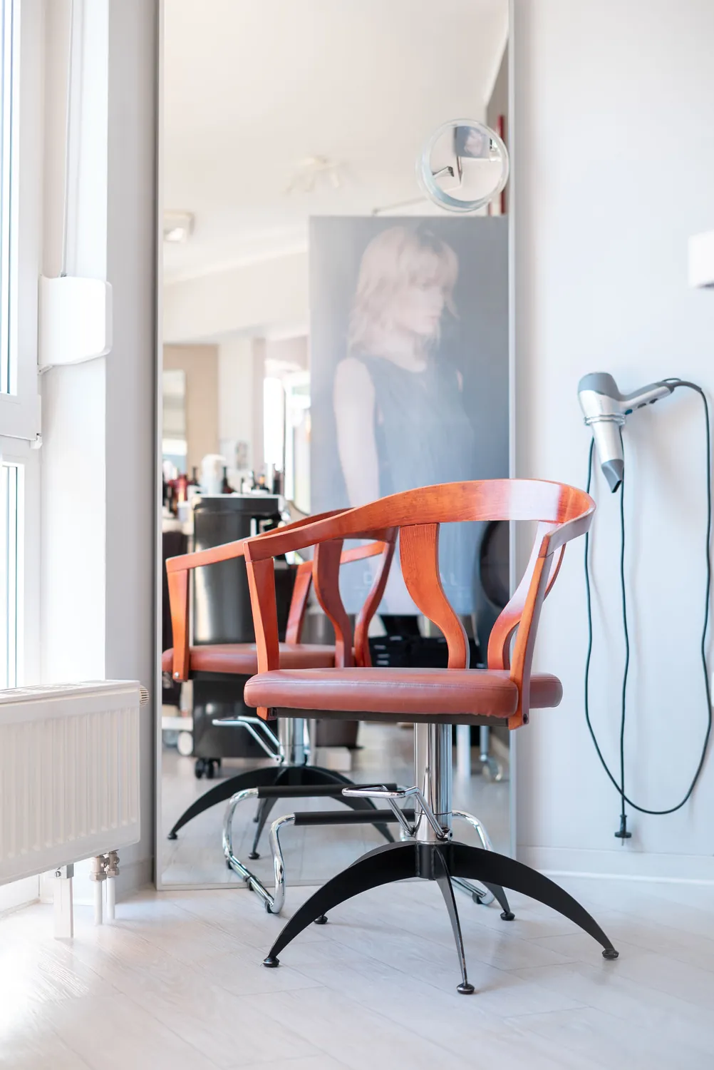 Orangefarbener Friseurstuhl vor dem Spiegel im Salon P in Wendisch Rietz